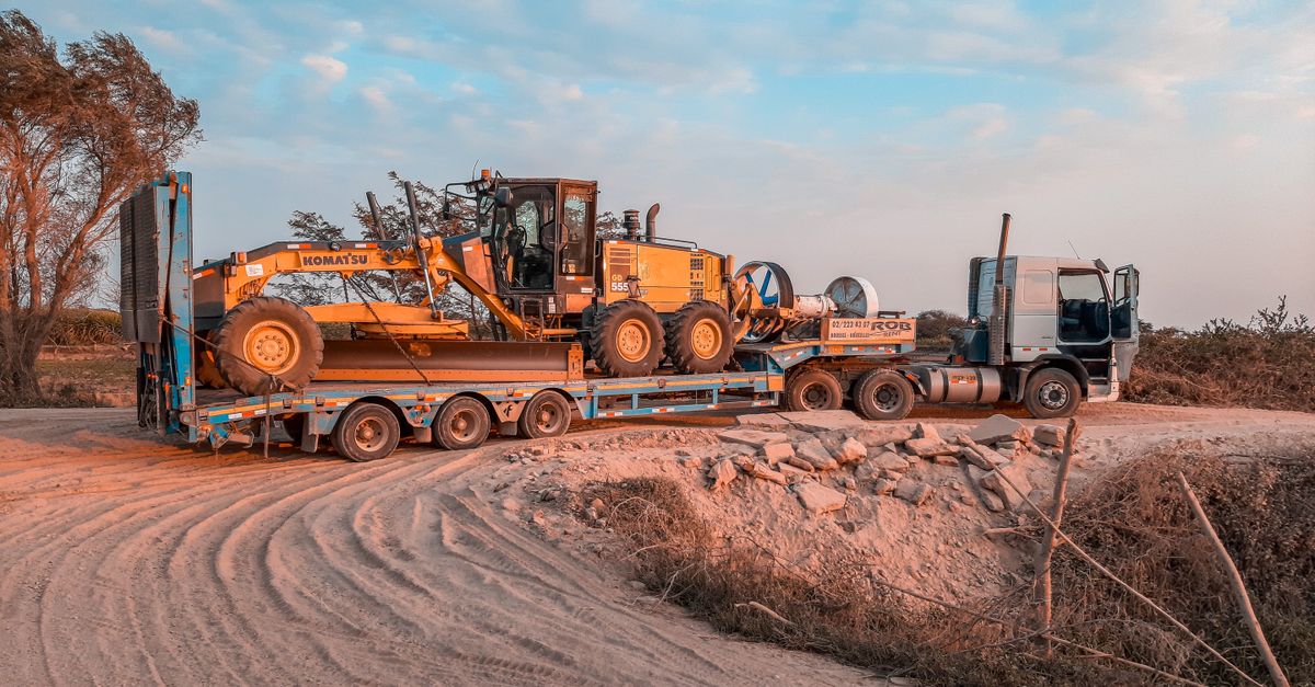 Schwerlasttransporter mit Baumaschine als Beispiel für flexibel gemietete Unternehmensressourcen