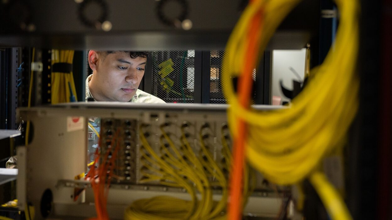 Techniker arbeitet zwischen Netzwerkkabeln und IT-Anlagen in einem Serverraum